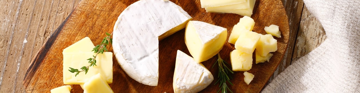 Photo of a cheese board with several types of cheese on it.