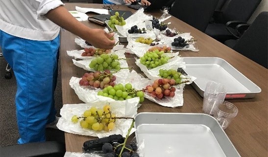 Photo of a person choosing between several types of grapes.