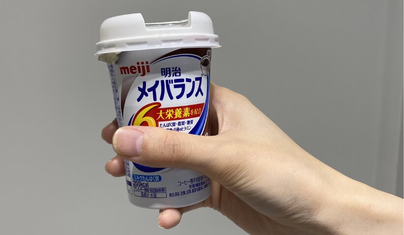 Photo a hand holding a bottle of Meiji MeiBalance.