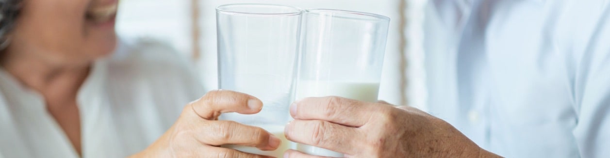 Photo of two people toasting with drinks.