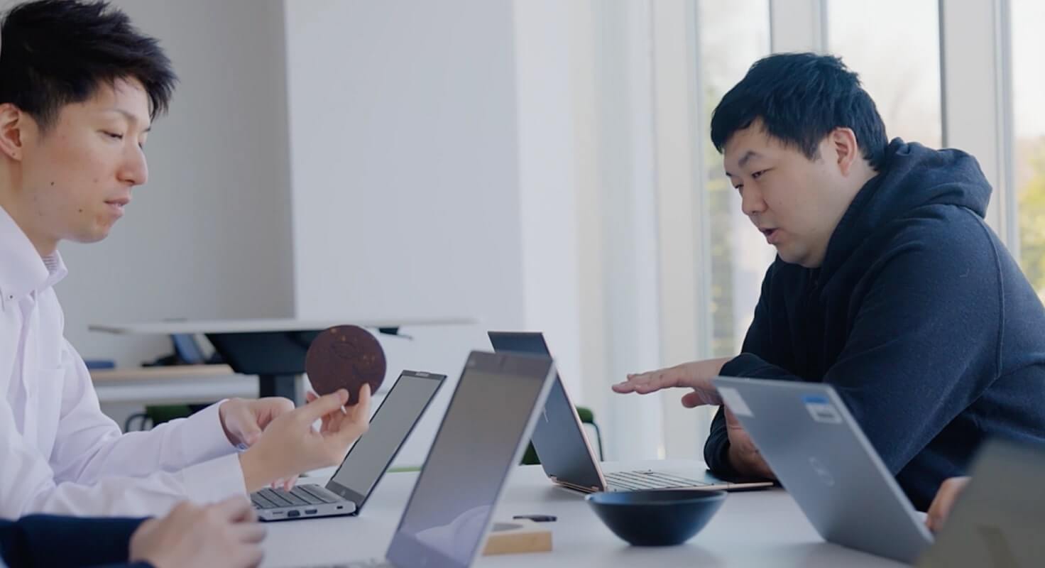 photo of Hareyama and Machida discussing a sample of cocoa husk