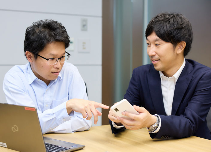 写真：赤ちゃんノートのアプリ表示を確認する渡部と増田